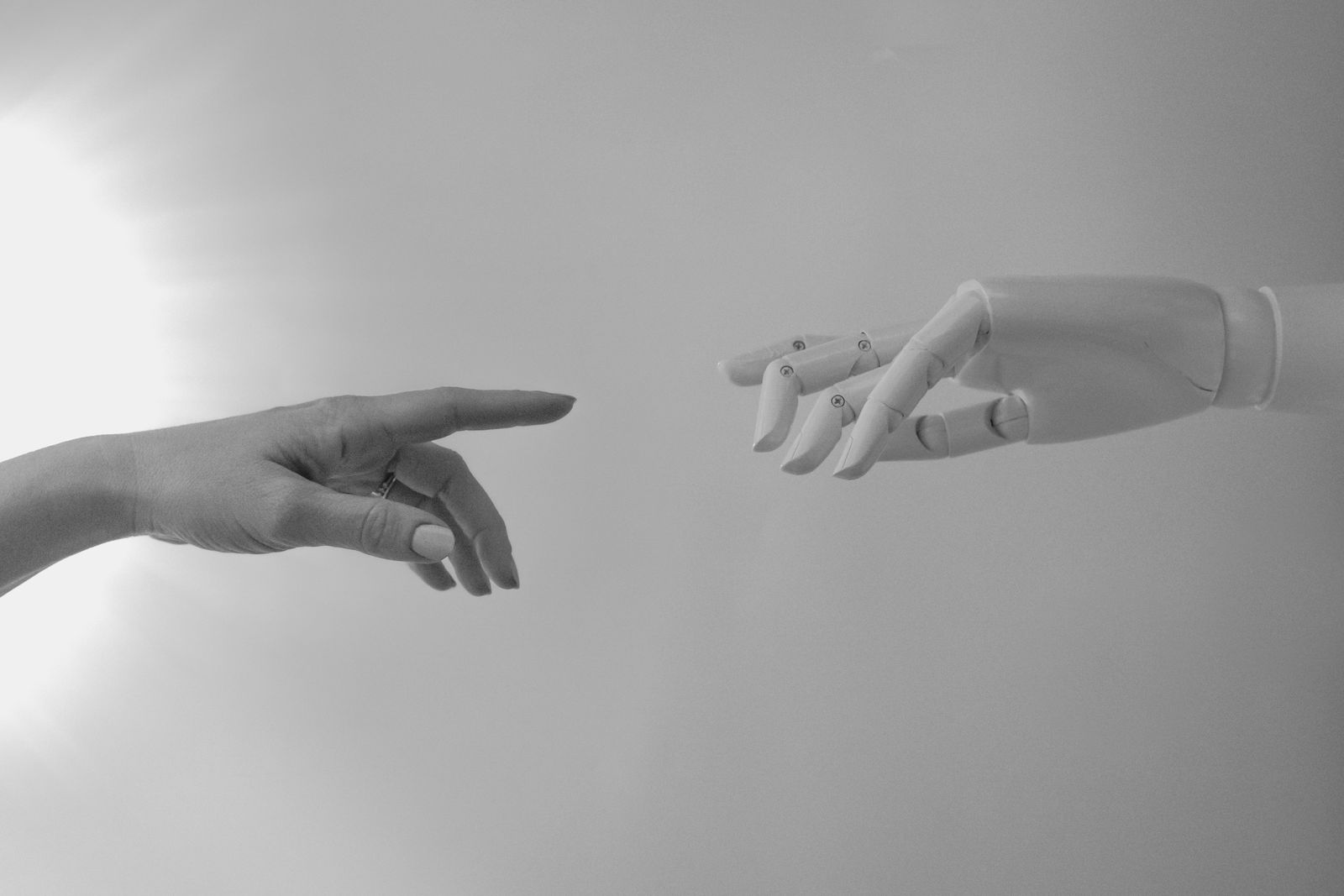 A human hand reaching toward a robot hand, the human-and-AI collaboration behind The Pixel Mark's operating model