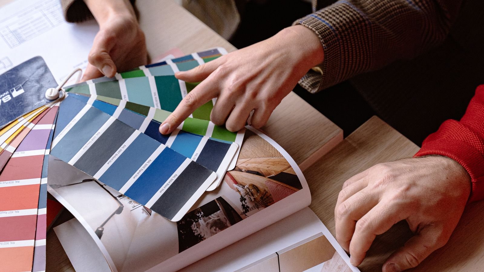Two interior designers reviewing colour swatches and material samples at a table